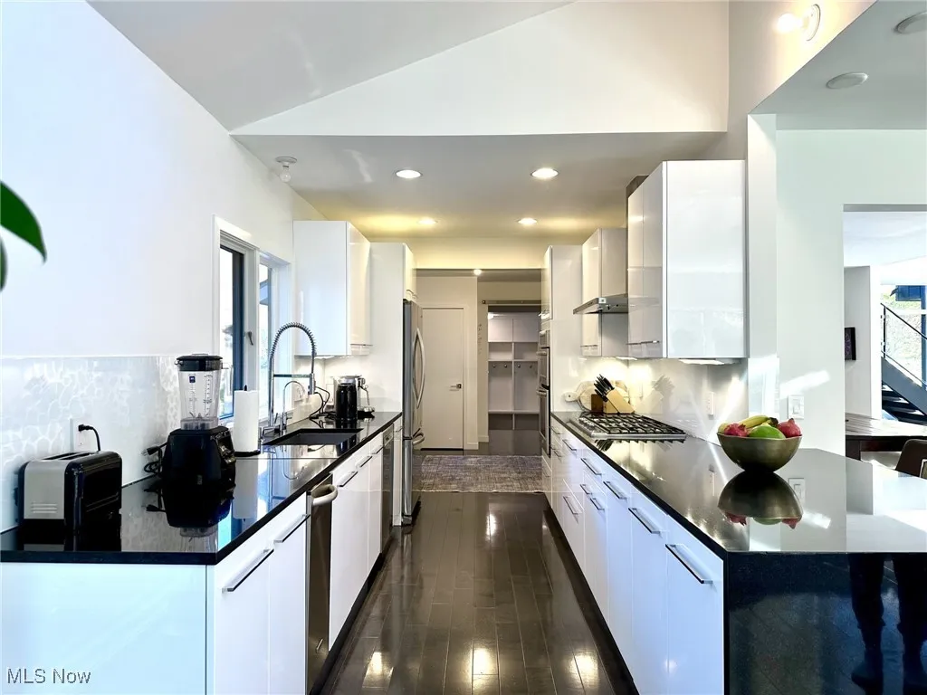 Kitchen with sink, white cabinets, and vaulted ceiling