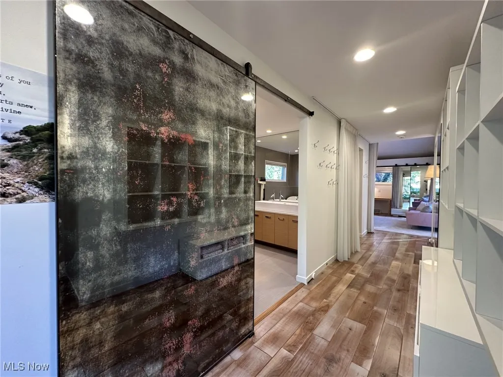 Corridor with a healthy amount of sunlight, a barn door, and light hardwood / wood-style flooring