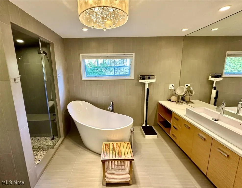 Bathroom featuring independent shower and bath, vanity, a chandelier, and a wealth of natural light