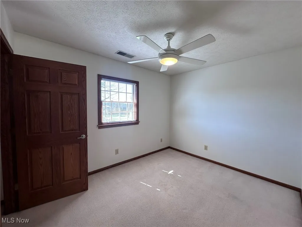 Unfurnished bedroom with visible vents, light carpet, a textured ceiling, and baseboards