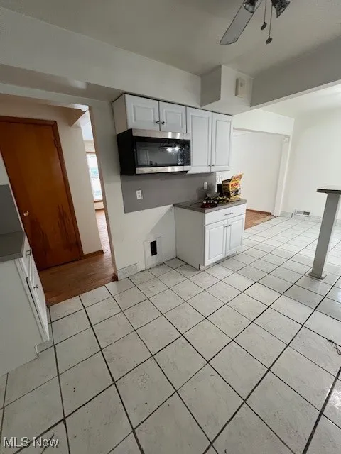 Kitchen featuring white cabinets, ceiling fan, and light tile patterned flooring