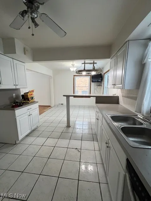 Kitchen with sink, light tile patterned floors, white cabinets, and dishwasher