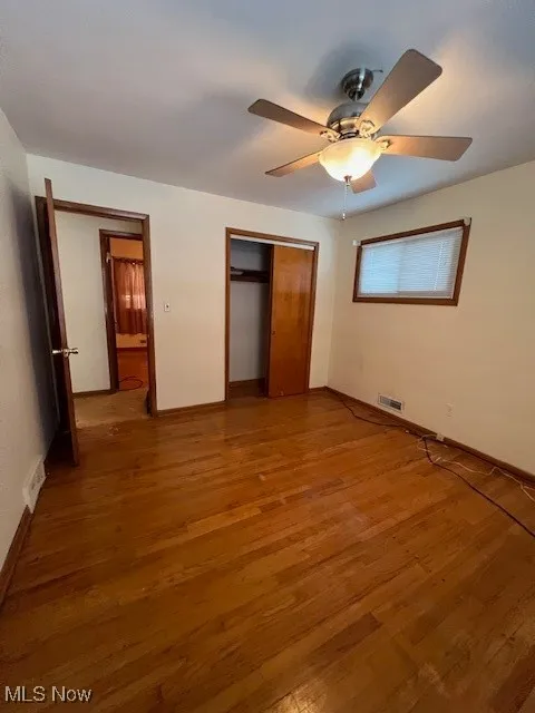 Unfurnished bedroom featuring wood-type flooring, a closet, and ceiling fan
