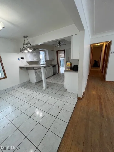 Kitchen featuring white cabinets, ceiling fan, pendant lighting, kitchen peninsula, and dishwashing machine