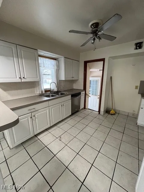 Kitchen featuring white cabinets, dishwasher, decorative backsplash, and sink
