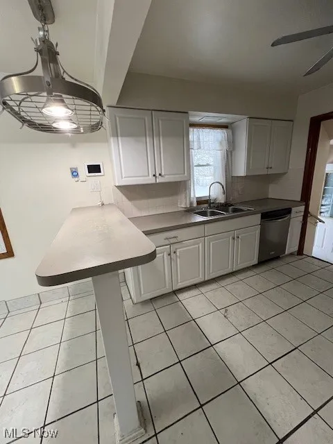 Kitchen featuring white cabinets, dishwasher, a breakfast bar, sink, and tasteful backsplash