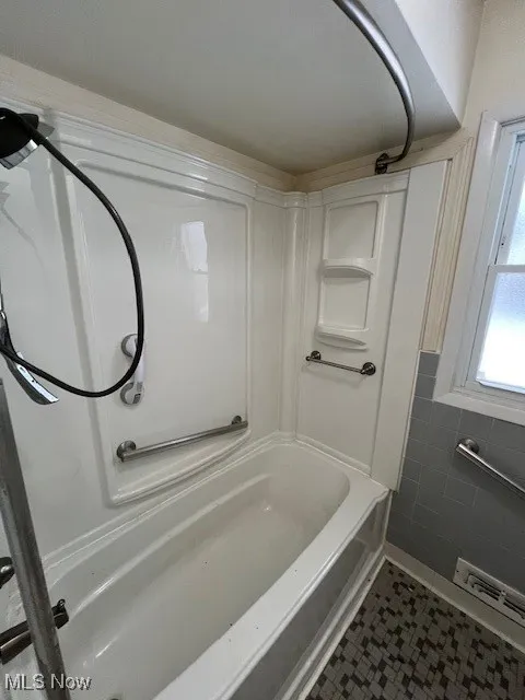 Bathroom with tile walls, shower / bathing tub combination, and tile patterned floors
