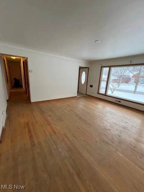 Unfurnished living room with ornamental molding and wood-type flooring