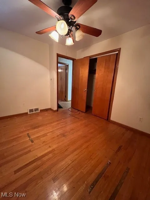 Unfurnished bedroom featuring light wood-type flooring, ceiling fan, and a closet