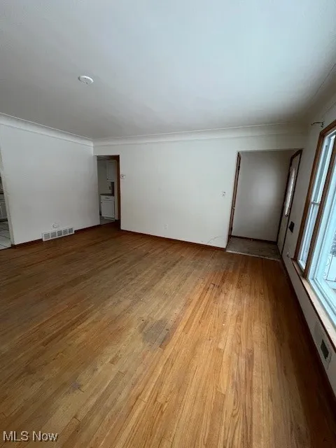 Empty room featuring light wood-type flooring and ornamental molding