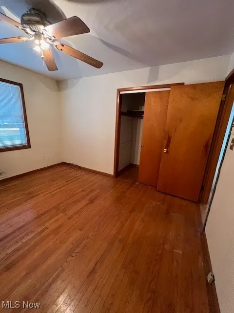 Unfurnished bedroom with ceiling fan, a closet, and hardwood / wood-style floors