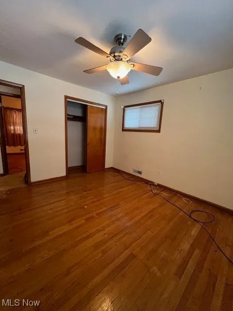 Unfurnished bedroom with wood-type flooring, a closet, and ceiling fan