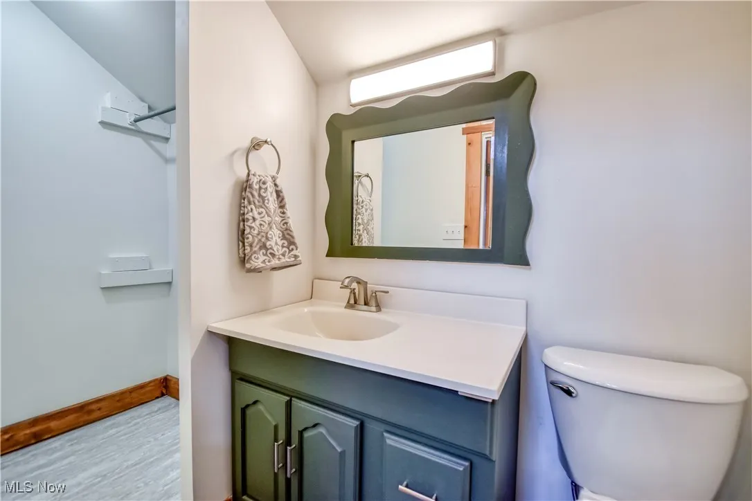 Bathroom with vanity, toilet, wood finished floors, and baseboards