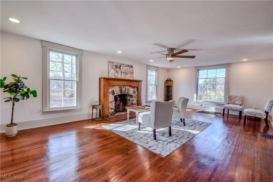 Living room with baseboards, recessed lighting, ceiling fan, a stone fireplace, and hardwood / wood-style flooring