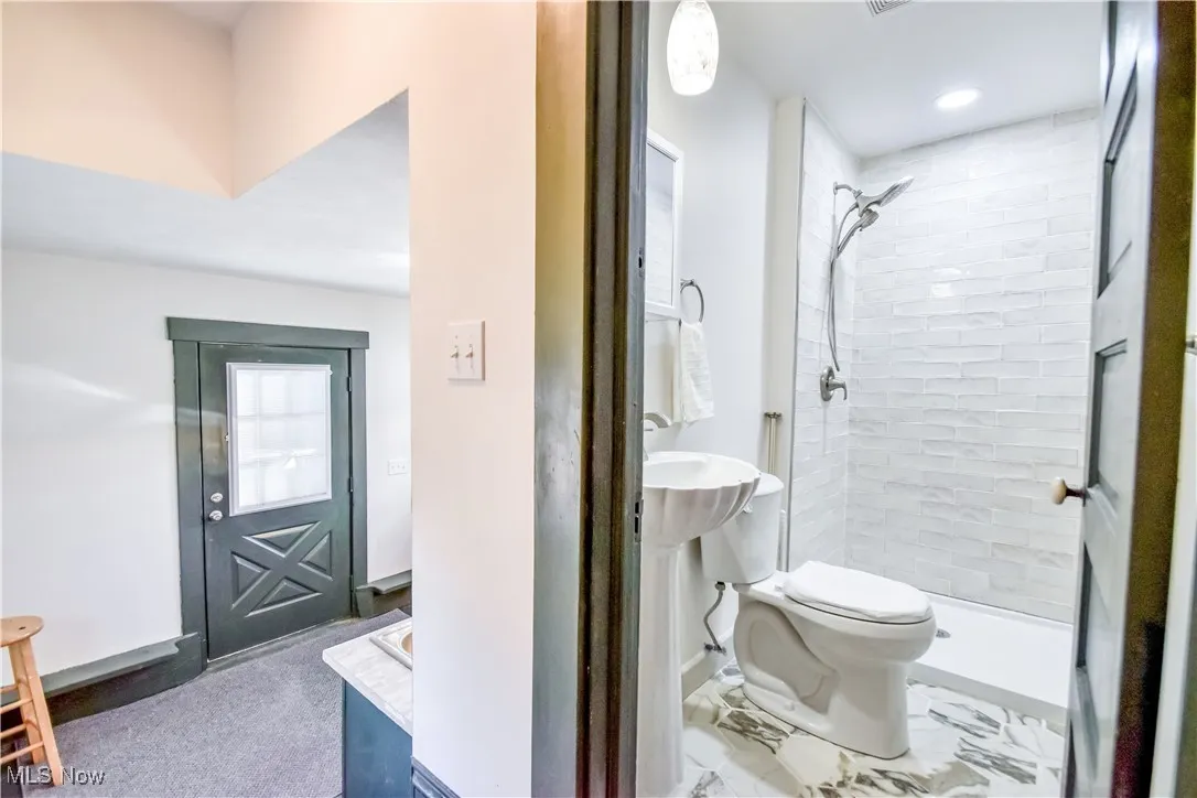 Full bathroom with a tile shower, visible vents, and toilet