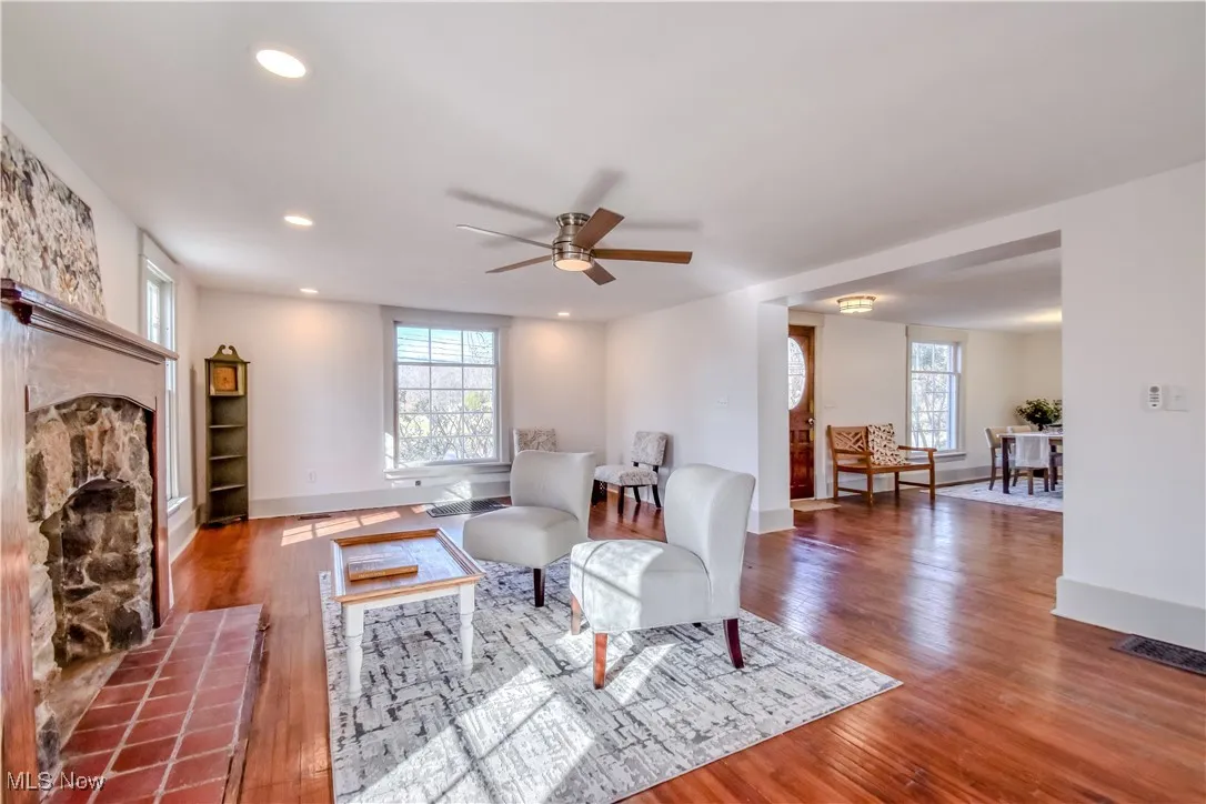 Living area featuring ceiling fan, plenty of natural light, wood finished floors, and a tile fireplace