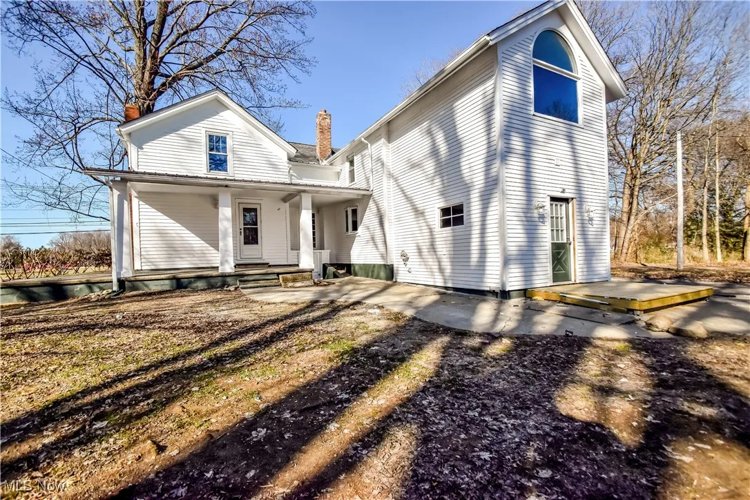 Back of property with covered porch and a chimney