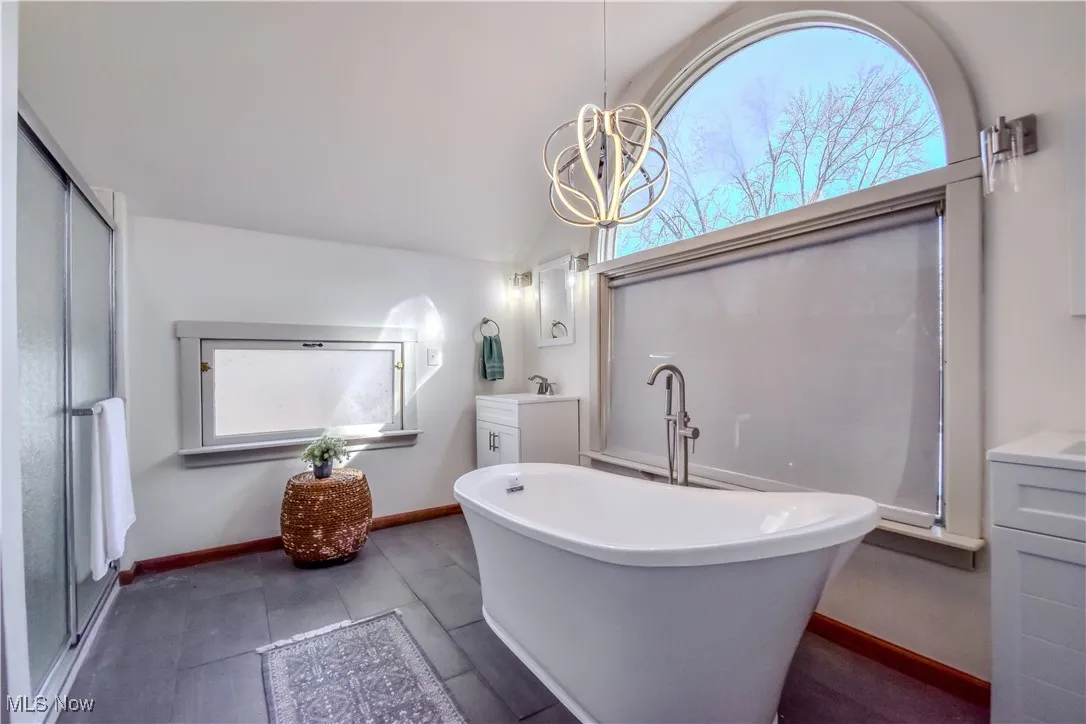 Full bath featuring a shower stall, baseboards, vaulted ceiling, a freestanding tub, and vanity