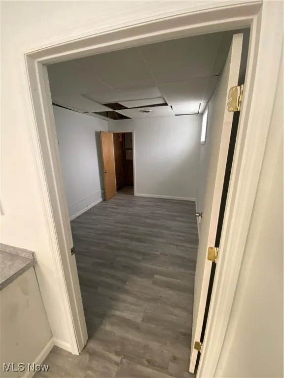 Corridor with dark hardwood / wood-style flooring and a paneled ceiling