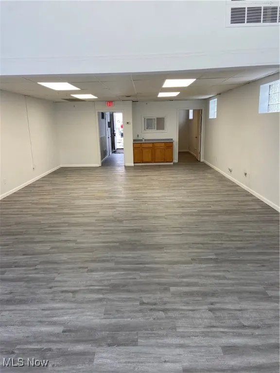 Basement with dark wood-type flooring and a paneled ceiling