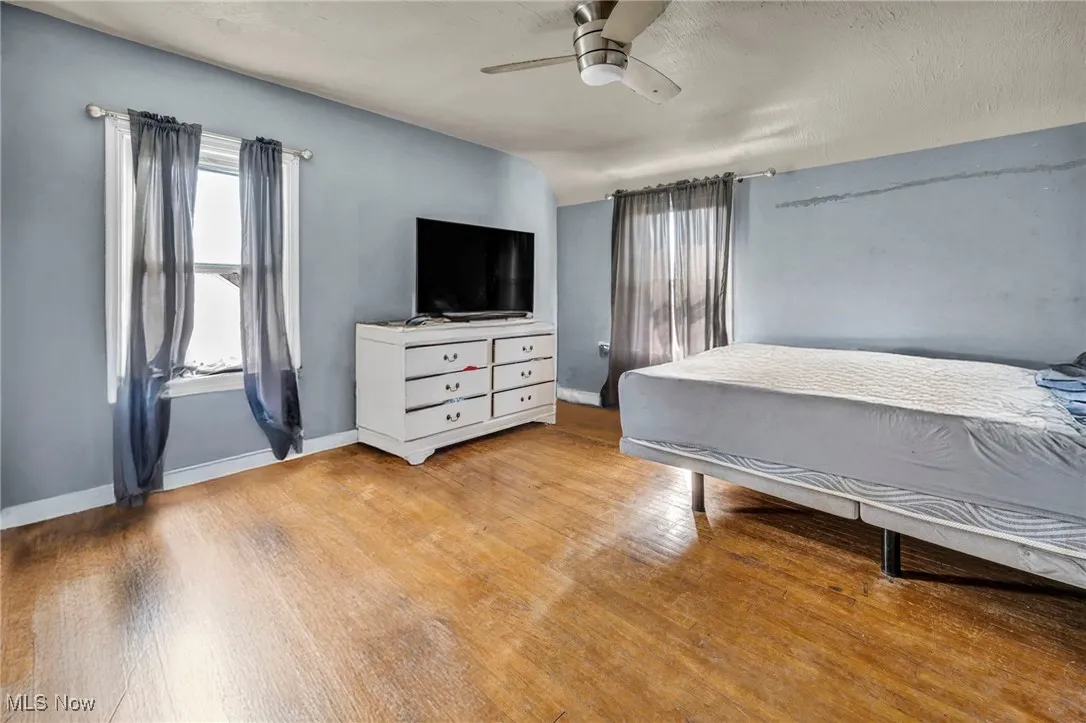 Bedroom featuring wood finished floors, baseboards, and ceiling fan