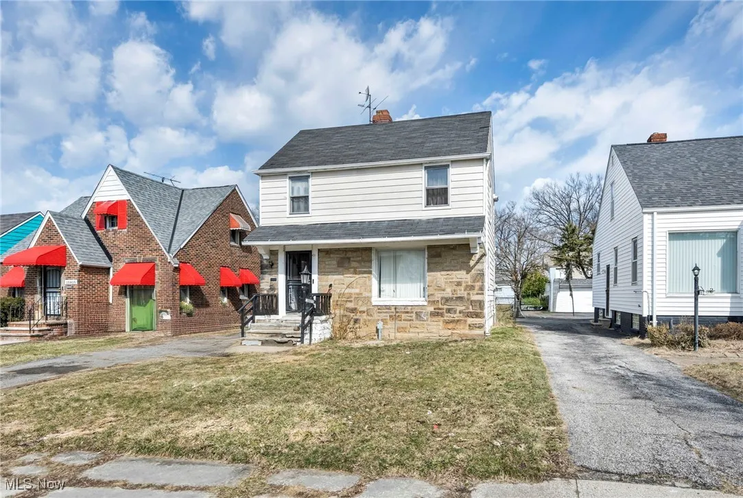 Traditional home with an outbuilding, stone siding, a front yard, a shingled roof, and a chimney