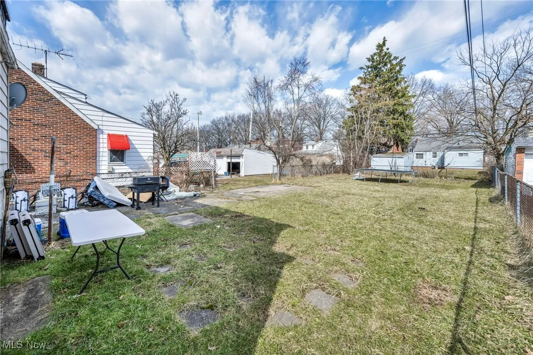 View of yard with a trampoline and fence
