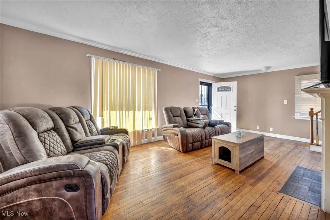 Living area featuring a textured ceiling, crown molding, and wood-type flooring