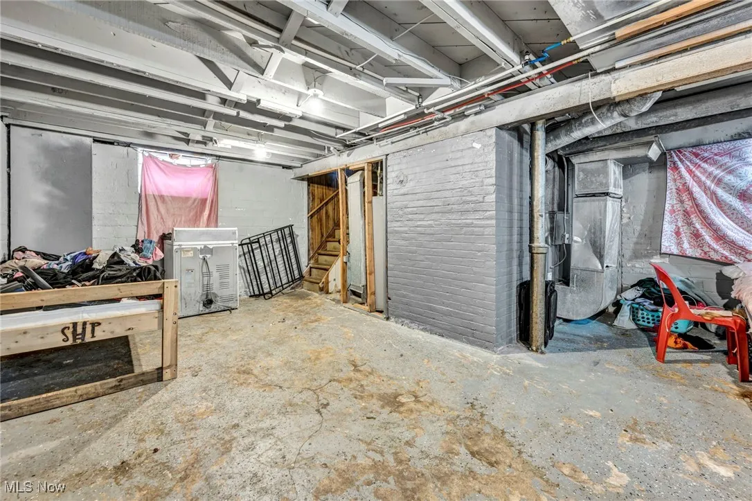 Unfinished basement featuring stairway and heating unit