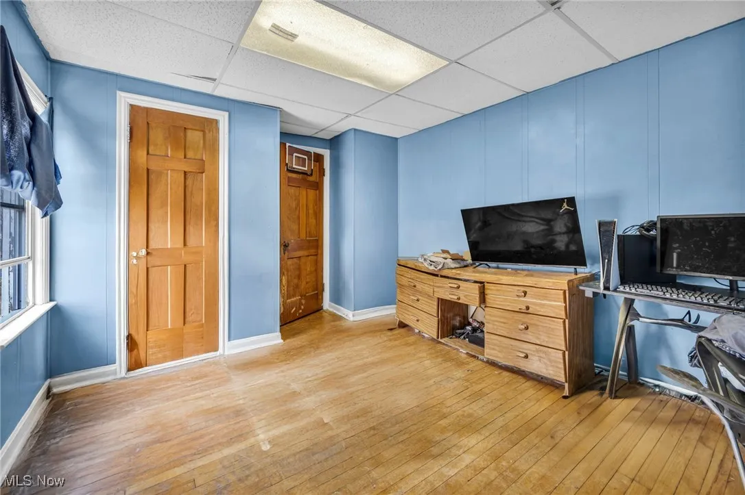 Bedroom with light wood-style flooring, a paneled ceiling, and baseboards