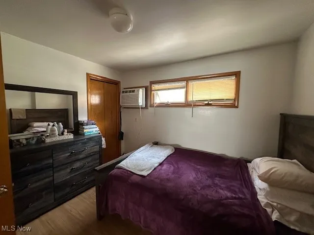 Bedroom 2 downstairs unit with wood finished floors, a wall mounted AC, and a closet