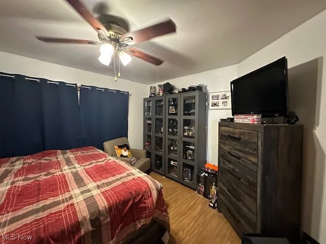 Bedroom 1 downstairs with wood finished floors and ceiling fan