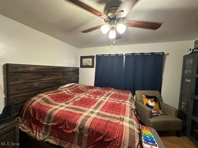 Bedroom 1 downstairs featuring ceiling fan and wood finished floors