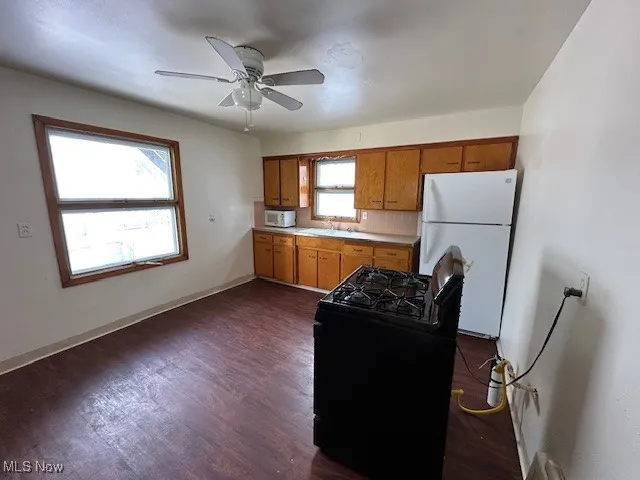 Kitchen featuring ceiling fan, plenty of natural light, backsplash, and white appliances