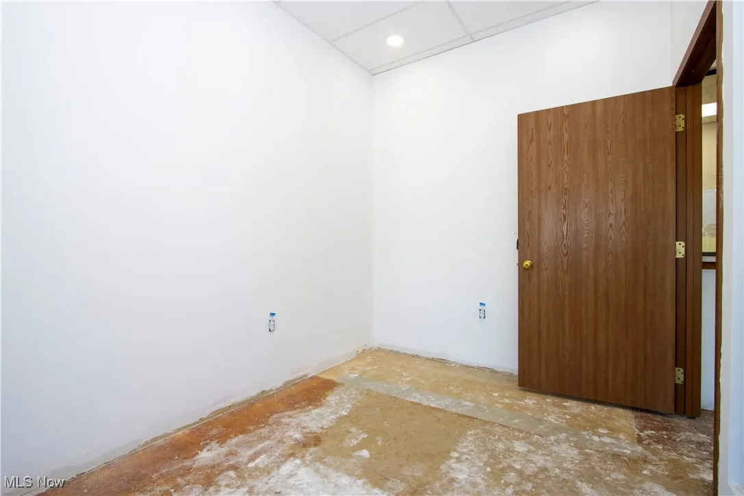 Empty room featuring a paneled ceiling, unfinished concrete floors, and recessed lighting