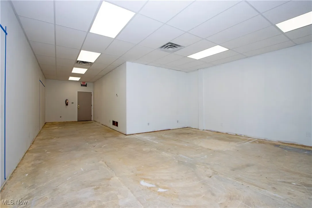 Unfurnished room featuring a paneled ceiling and unfinished concrete flooring
