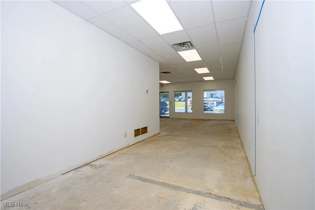 Unfurnished room with a drop ceiling and concrete flooring