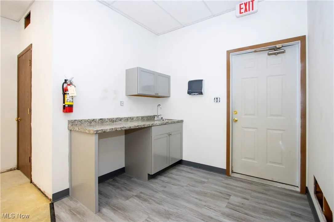 Kitchen featuring gray cabinetry, a drop ceiling, light wood-type flooring, and light countertops
