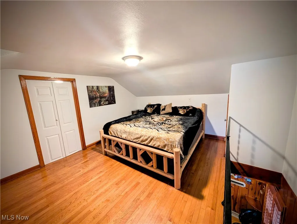 Bedroom with a closet, lofted ceiling, and wood-type flooring