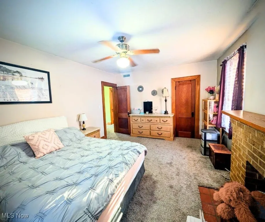 Bedroom with light colored carpet, ceiling fan, and visible vents