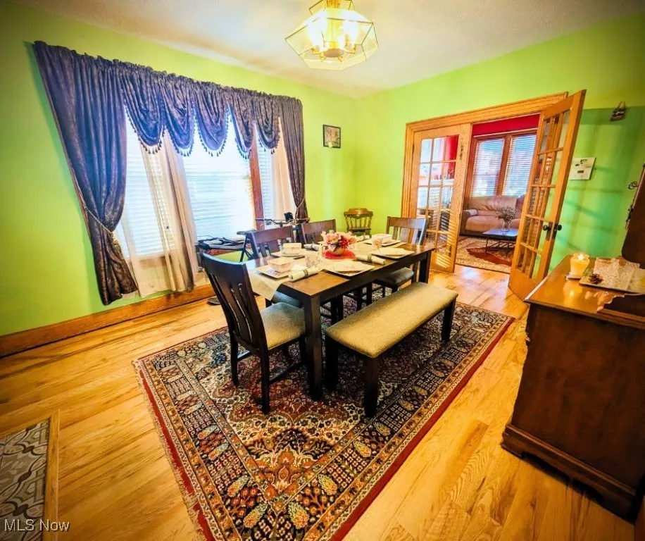 Dining space featuring a wealth of natural light, french doors, light wood finished floors, and an inviting chandelier