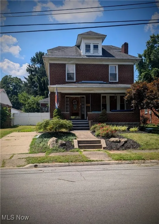 Traditional style home featuring brick siding, covered porch, and a chimney