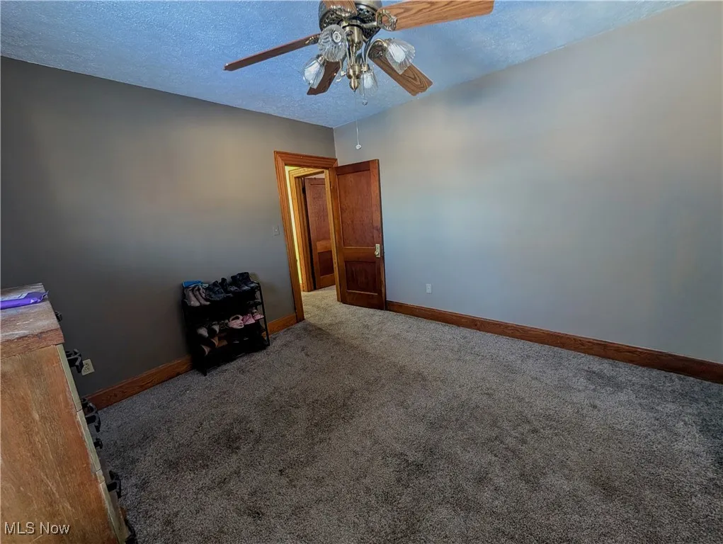 Carpeted spare bedroom with a textured ceiling and ceiling fan