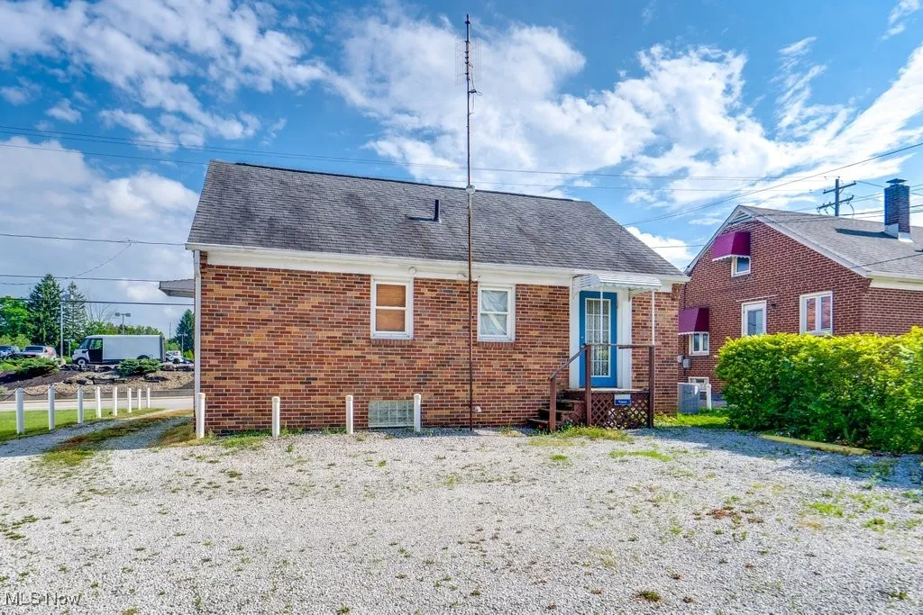 Back of property with brick siding and a shingled roof