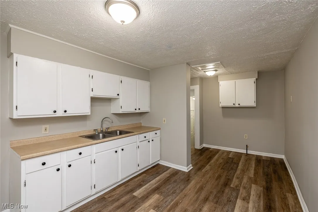 Kitchen with white cabinets, dark hardwood / wood-style floors, sink, and a textured ceiling