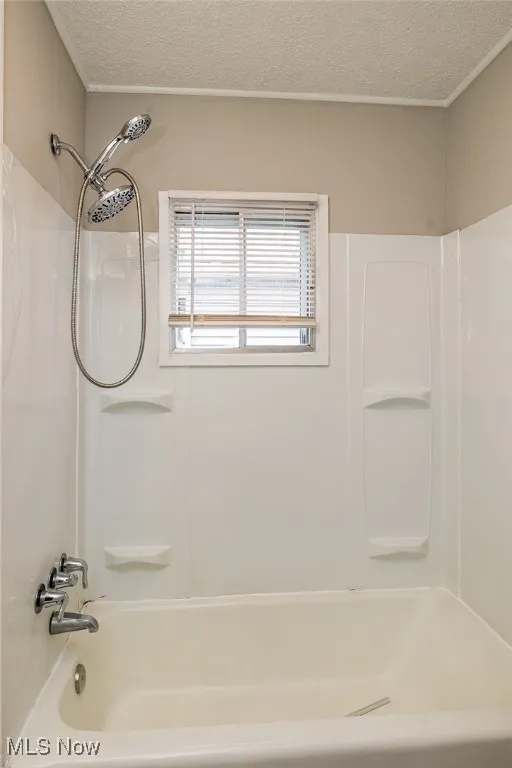 Bathroom featuring a textured ceiling and washtub / shower combination