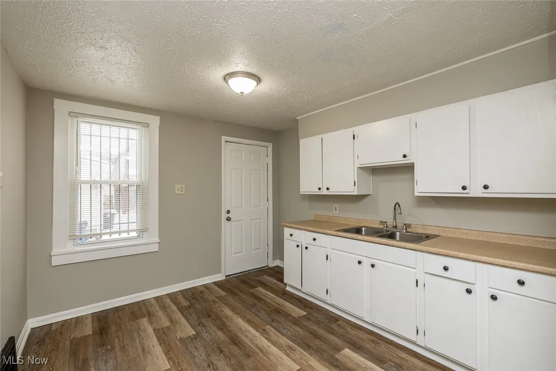 Kitchen featuring a textured ceiling, white cabinetry, dark hardwood / wood-style floors, and sink