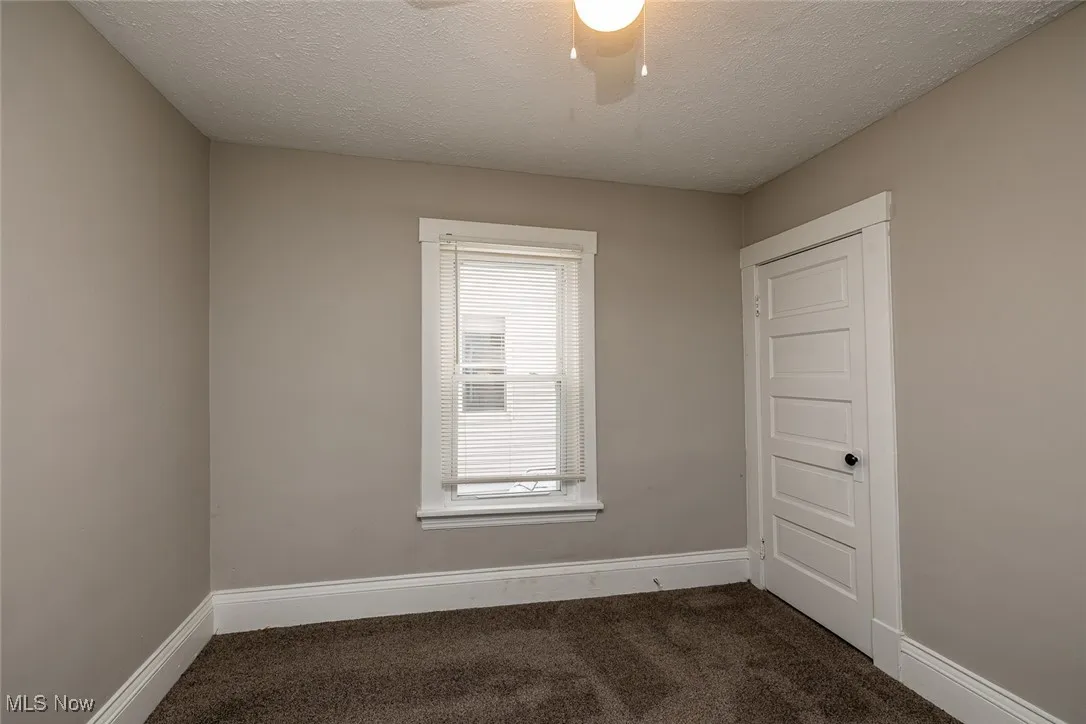 Carpeted spare room featuring a textured ceiling and ceiling fan