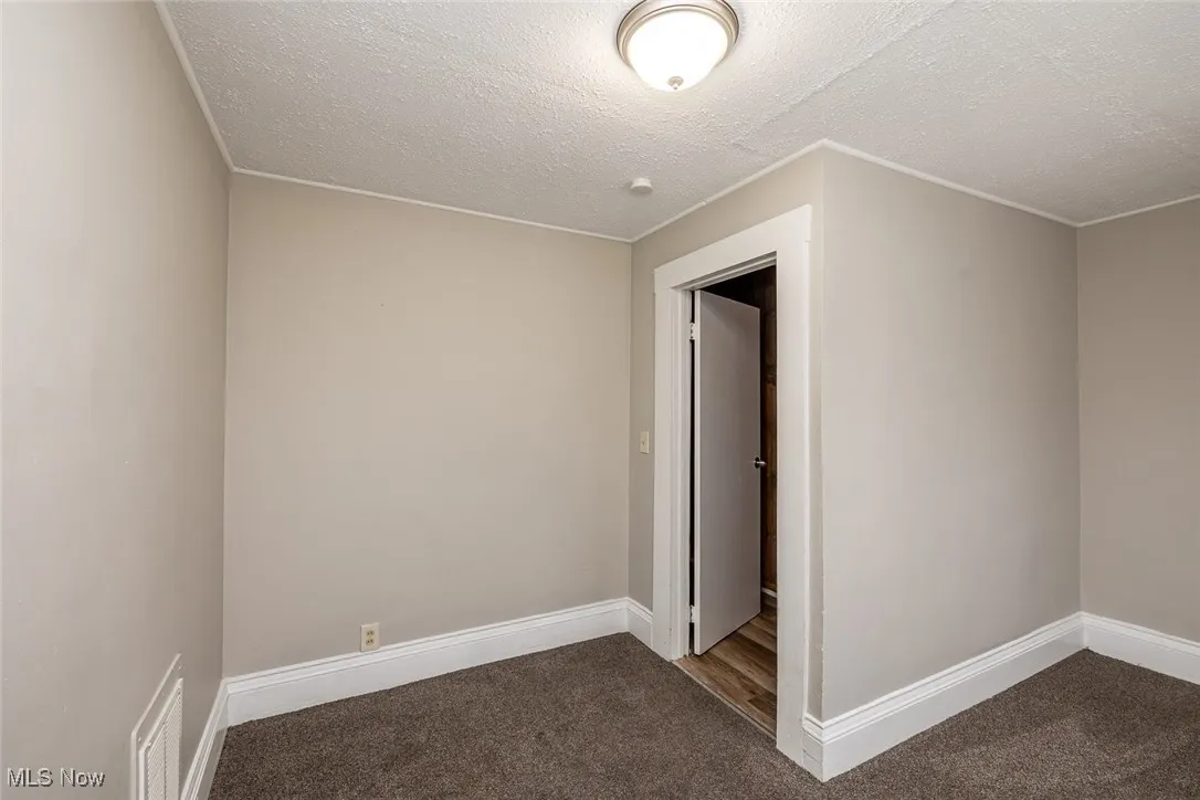 Carpeted empty room with a textured ceiling