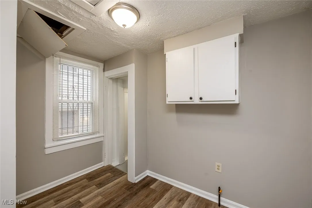 Laundry room featuring a textured ceiling and dark wood-type flooring